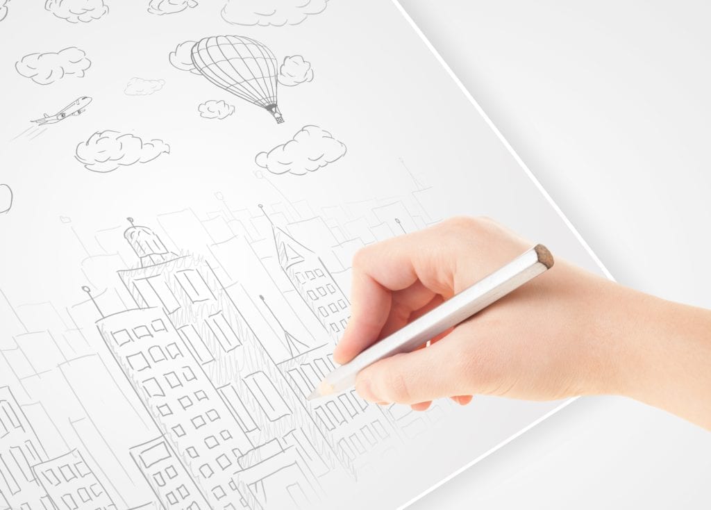 person's hand drawing a city scene in pencil