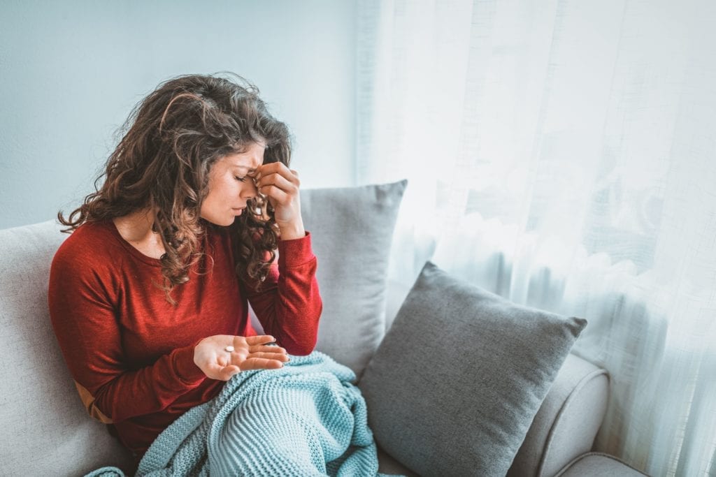 woman with headache and medication in her hand