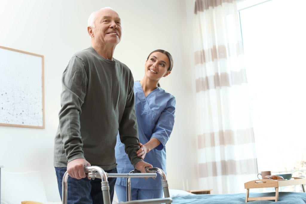 nurse helping older man with walker