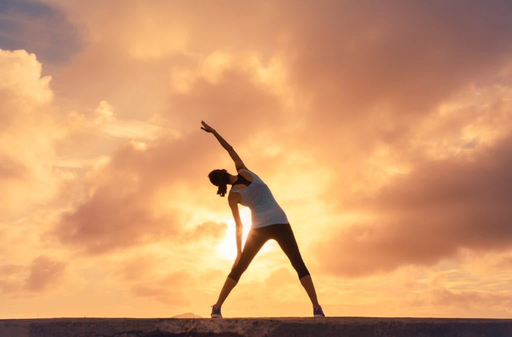 woman doing yoga against the sunset