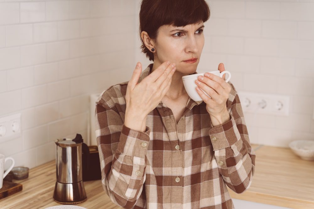 woman trying to smell her coffee