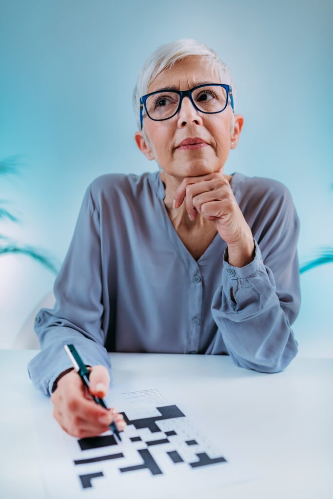 senior woman doing a crossword and staring off into space thinking