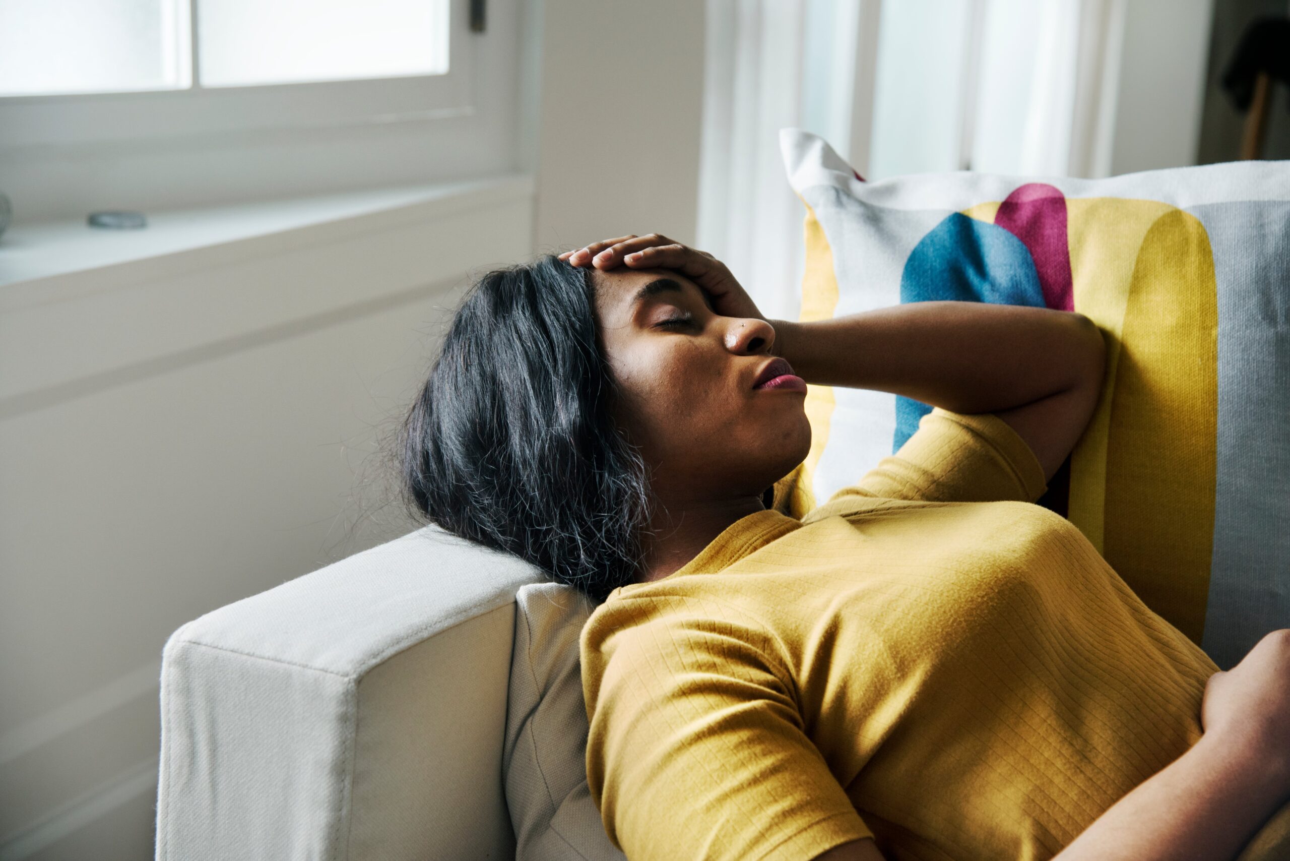 woman laying on couch with migraine
