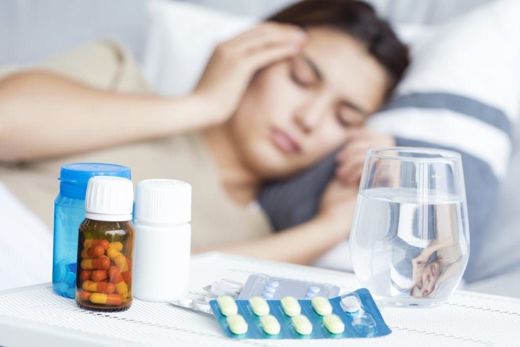 woman in bed with a headache from taking too many medications