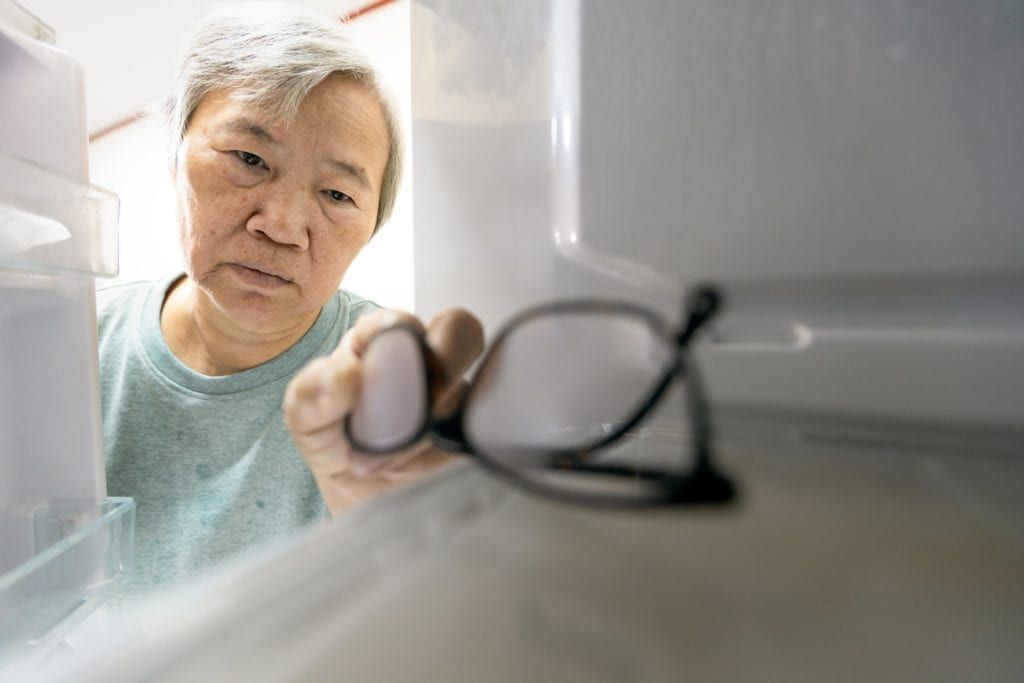 senior woman confused putting her glasses in the fridge