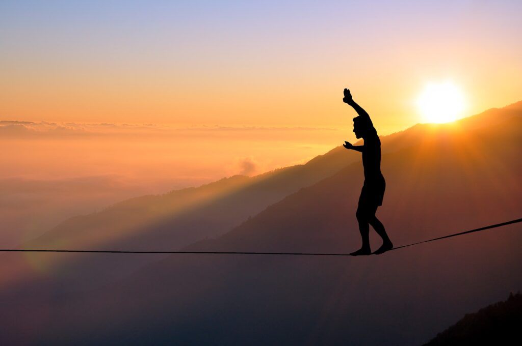 man balancing on a tight rope across a canyon