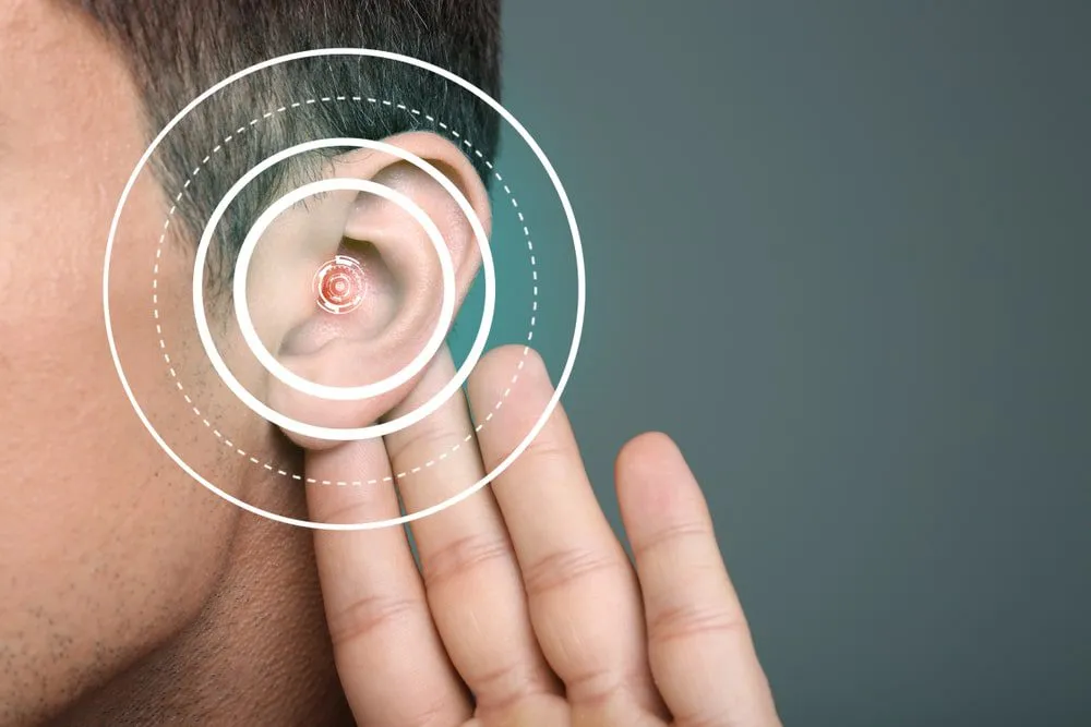 man with hand to his ear to indicate hearing loss