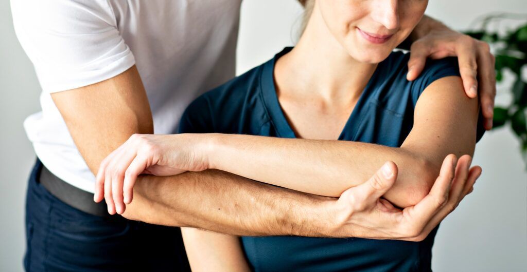 woman and doctor evaluating woman's arm and elbow