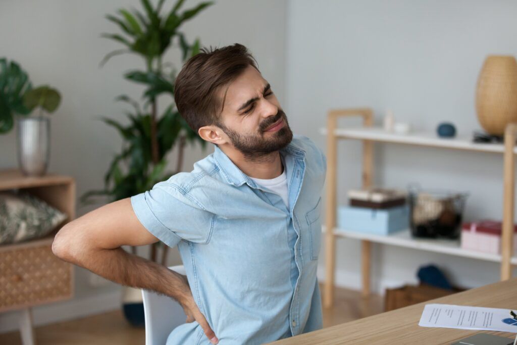 man cringing at his desk with back pain