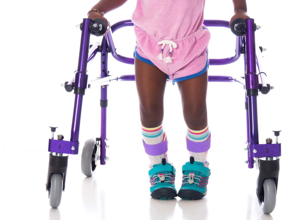 young girl with cerebral palsy wearing orthotics on her legs and using a walker to move