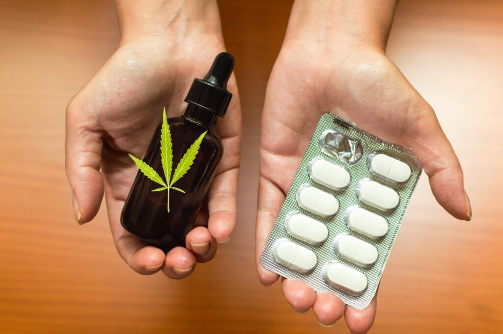 Therapeutic marijuana concept: hands showing and comparing natural CBD oil made with cannabis and traditional medicines.