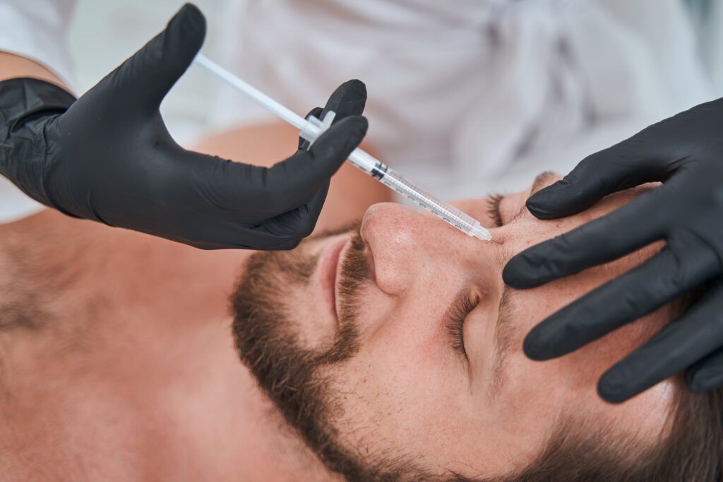man getting botox injected in between his eyebrows
